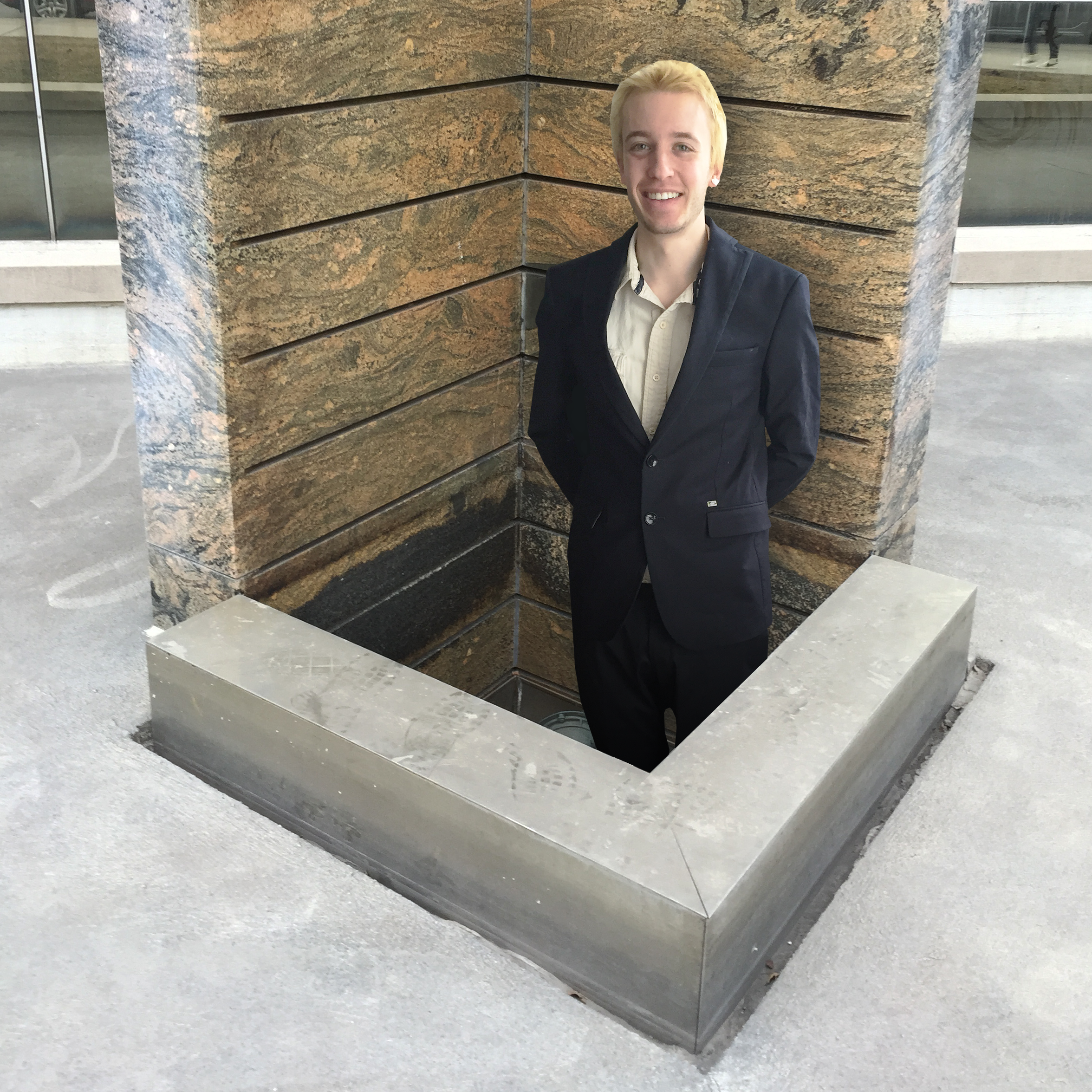 Butler stanind and smiling towards the camera in an empty fountion